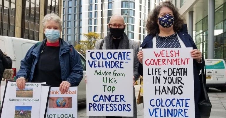 Three campaigners holding posters for better cancer services