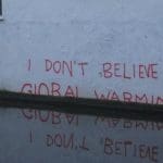 The expression "I don't believe in global warming" ironically slipping dpwn the wall into a puddle