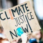 Placard at global climate justice protest reading ‘climate justice now’