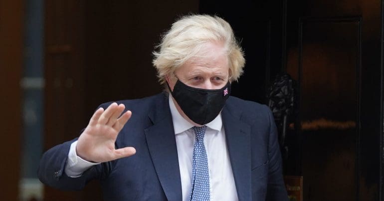 Boris Johnson waving with a mask on