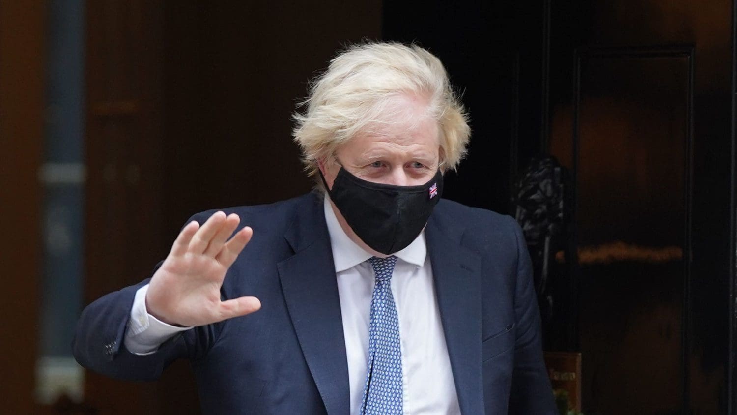 Boris Johnson waving with a mask on