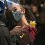 Protester with a flower standing in front of a police officer