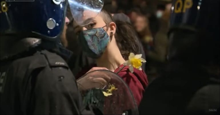 Protester with a flower standing in front of a police officer