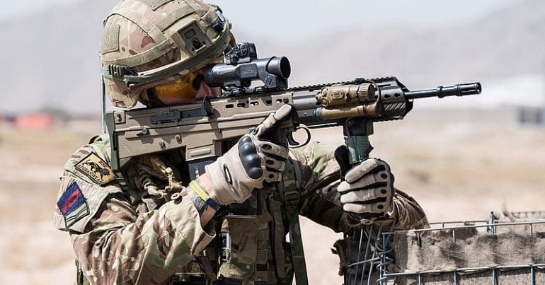 UK soldier aims rifle in Afghanistan.