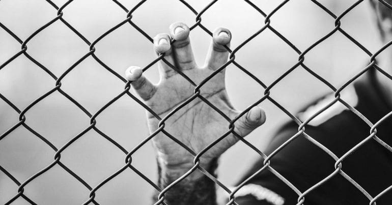 man holding chain-link fence