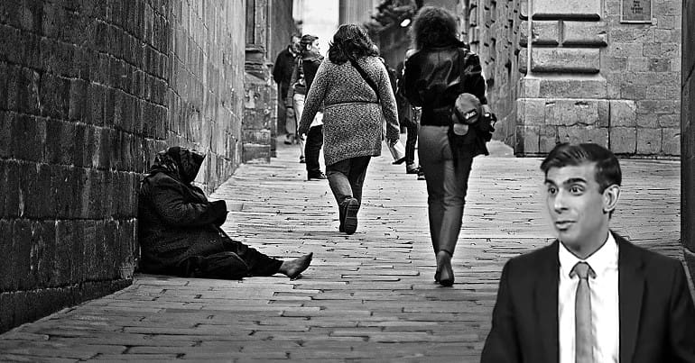 A homeless person sitting on the street with Rishi Sunak looking at them