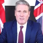 Keir Starmer sitting in front of two Union Jacks