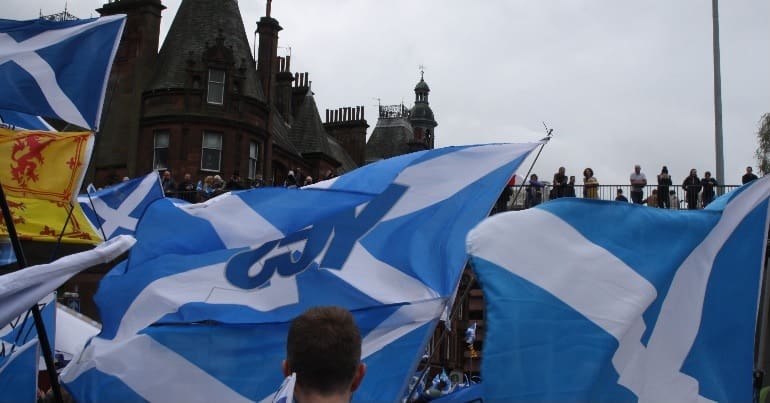 A Scottish independence march displaying several saltires, one defaced with the YES campaign logo