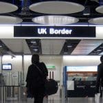 Two people walk away from the camera towards UK border checks at Heathrow airport.