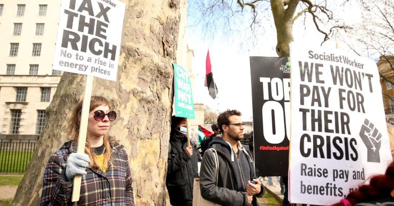 Protesters holding signs which read 'tax the rich'