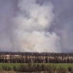Smoke billowing in the distance in a rural landscape