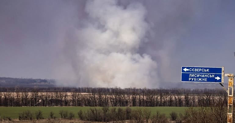 Smoke billowing in the distance in a rural landscape