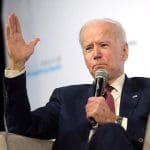 A seated Joe Biden gives a speech