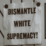 a sign saying "dismantle white supremacy"