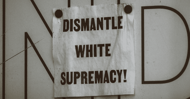 a sign saying "dismantle white supremacy"