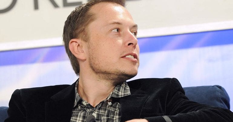Elon Musk turns to his left.