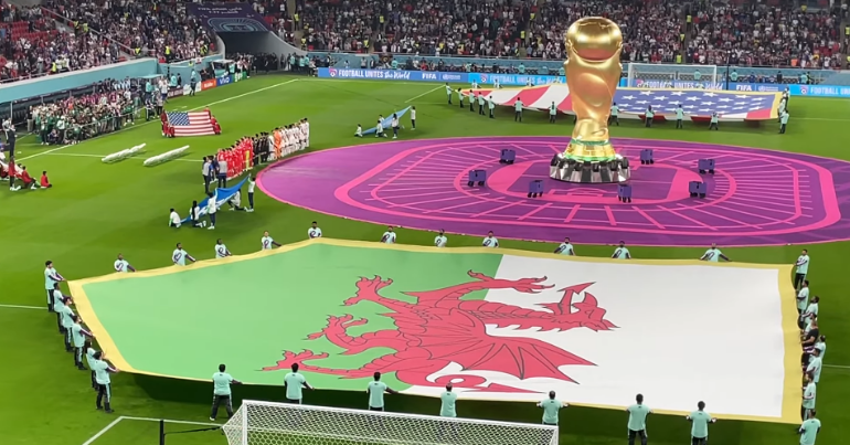 The Welsh flag being displayed on the pitch at the 2022 World Cup