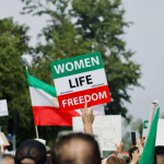 Iran protests, one person holds a sign saying "women, life, freedom"