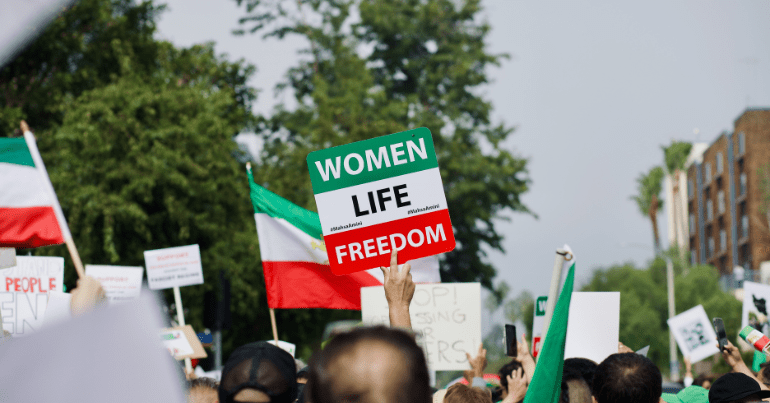 Iran protests, one person holds a sign saying "women, life, freedom"