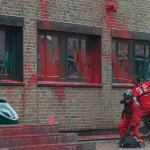 Palestin Action activists throwing a fire extinguisher at Elbit Syems offices which are covered in red paint