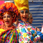 two panto dames stand back-to-back
