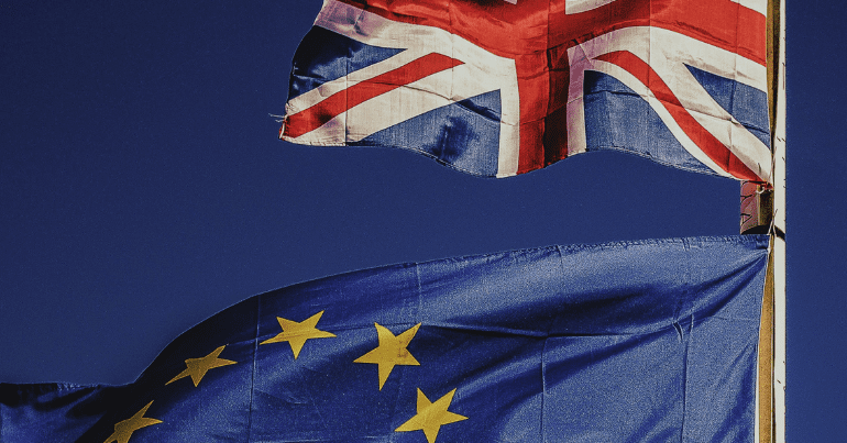 the Union Jack flutters; below the flag of the European Union