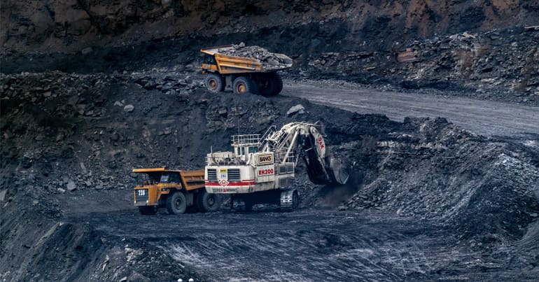 Open cast coal mine with a digger and two dumper trucks