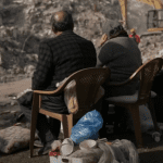 a couple look on at the rubble after an earthquake in Syria