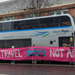 A protest around a bus with a banner that reads 'fair travel, not air travel'. XR Youth Bristol have been targeting buses as part of ongoing action
