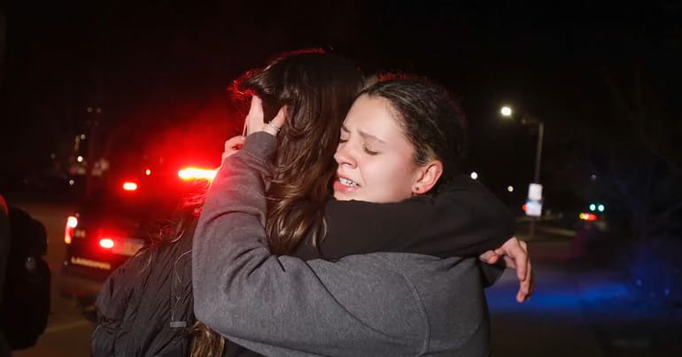 Two people hug in grief following gun violence and a mass shooting at Michigan State University
