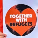 Woman holding a sign saying "Together With Refugees", the group that wrote an open letter against demanding politicians make a clear stand against racism in the UK