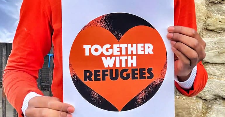 Woman holding a sign saying "Together With Refugees", the group that wrote an open letter against demanding politicians make a clear stand against racism in the UK