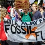 New IPCC report calls for wealthy nations to step up their climate ambitions. Climate protesters at a march. Banner reads: Walk away from fossil fuels and placard reads: Now do something about it.