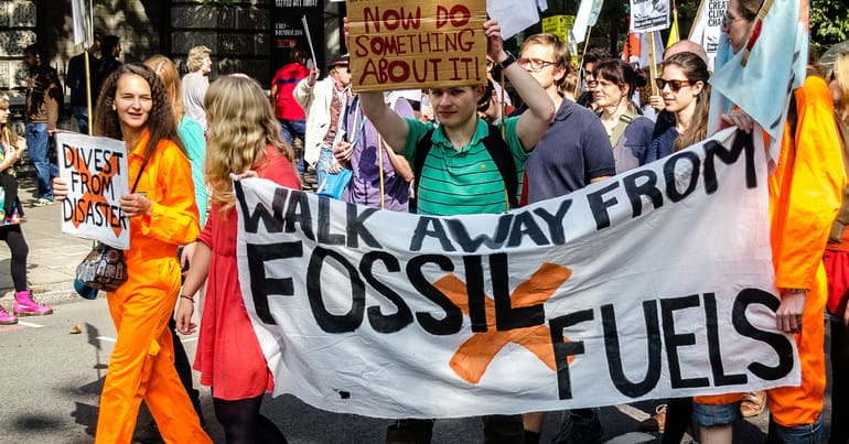 New IPCC report calls for wealthy nations to step up their climate ambitions. Climate protesters at a march. Banner reads: Walk away from fossil fuels and placard reads: Now do something about it.