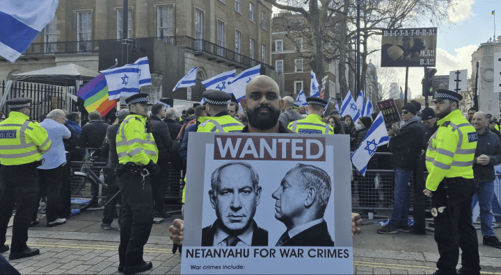 A man holds a sign saying "Wanted Netanyahu for war crimes" at a protest in London as Israel's PM visited 