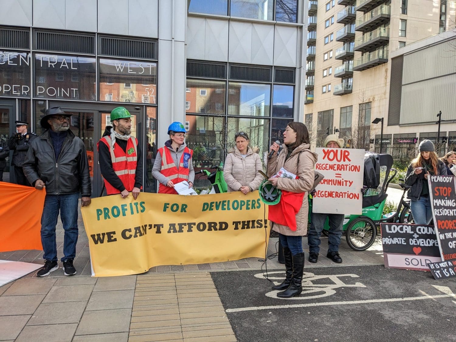 Residents protest outside a landlords office over housing while police watch in the background