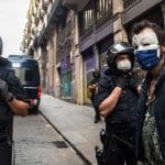 Spain and its police force are now implicated in a Spycops undercover police scandal. A picture of several Spanish cops and a protester wearing a Guy Fawkes mask