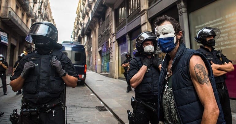 Spain and its police force are now implicated in a Spycops undercover police scandal. A picture of several Spanish cops and a protester wearing a Guy Fawkes mask