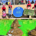 Protesters standing next to green water with floating inflatable poos in it. They included Extinction Rebellion - as the group unveiled another blue plaque