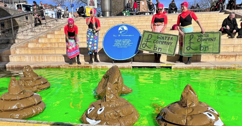 Protesters standing next to green water with floating inflatable poos in it. They included Extinction Rebellion - as the group unveiled another blue plaque