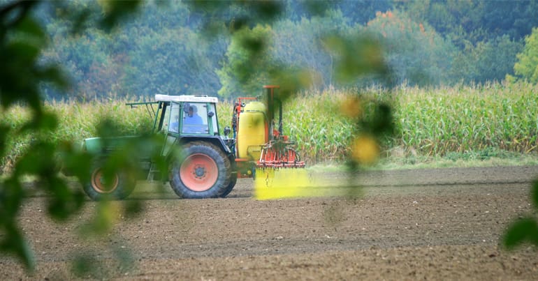 Tractor spraying pesticides onto ploughed field in Germany / EU.