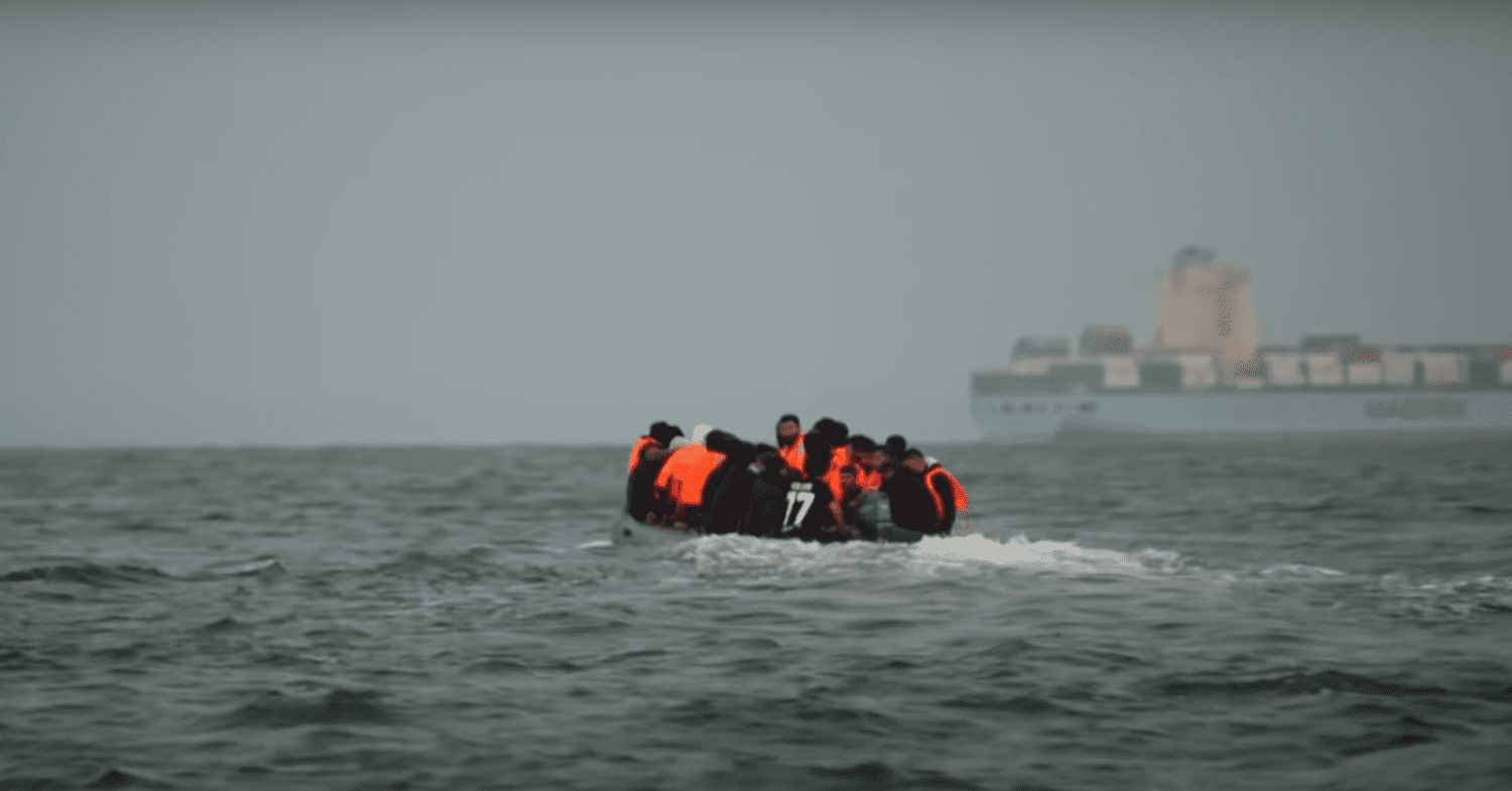 Refugees sit together on a small boat, wearing life vests, illegal migration bill, hostile environment