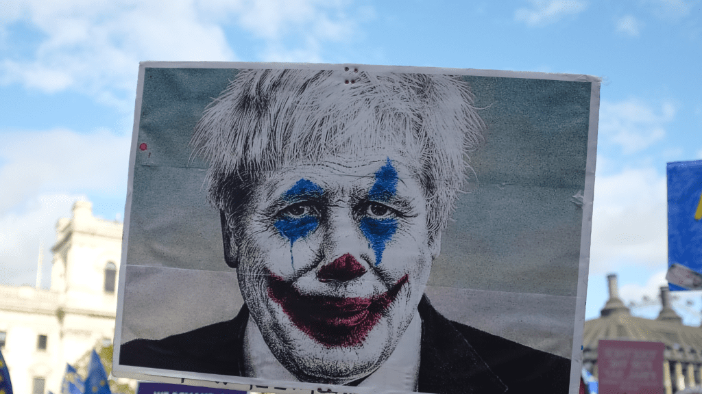 A protest sign depicting Boris Johnson as a clown. privileges committee