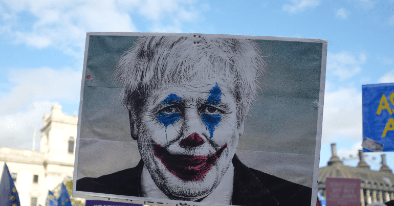 A protest sign depicting Boris Johnson as a clown. privileges committee