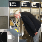 A visually impaired man leaning down to look at a ticket machine ticket office closures DfT