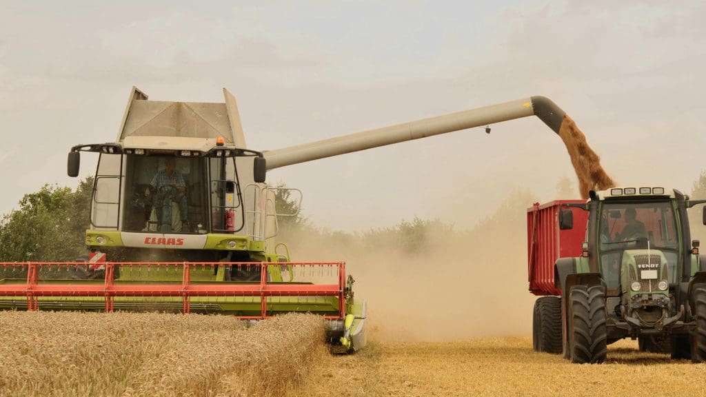 Combine harvester unloading wheat into a tractor in a field. Food Systems Summit UN WEF