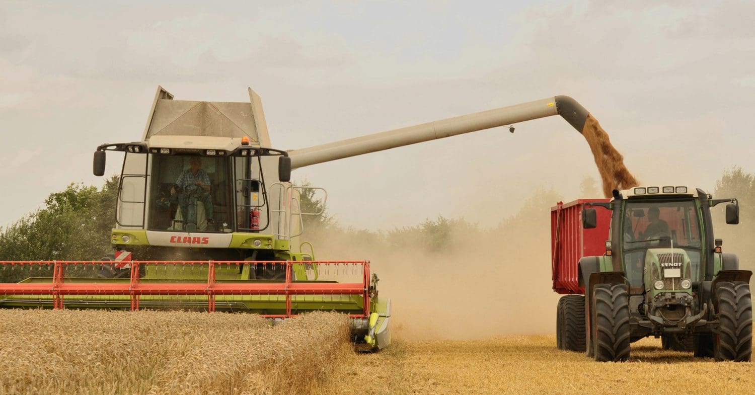 Combine harvester unloading wheat into a tractor in a field. Food Systems Summit UN WEF