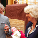 King Charles smiling and holding a jar of liquid
