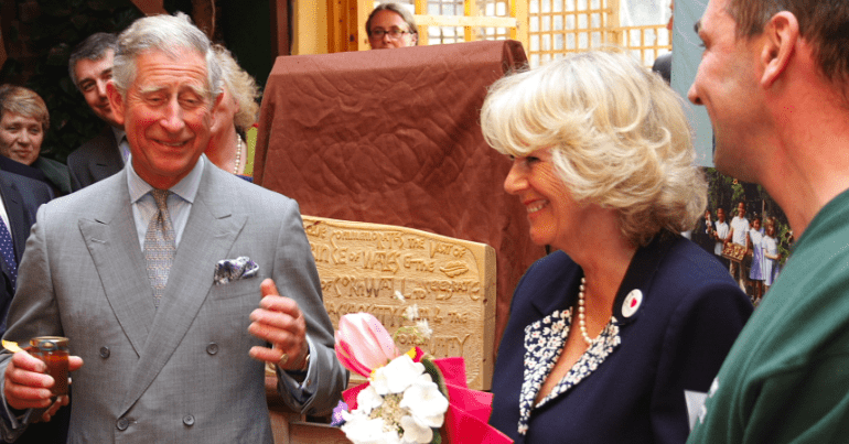 King Charles smiling and holding a jar of liquid