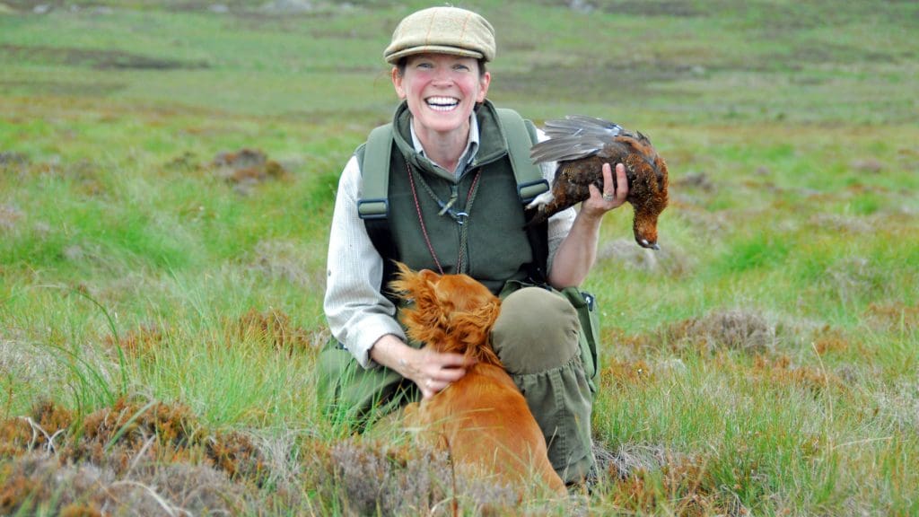 Woman with dog holds dead grouse during a shoot in Cumbria